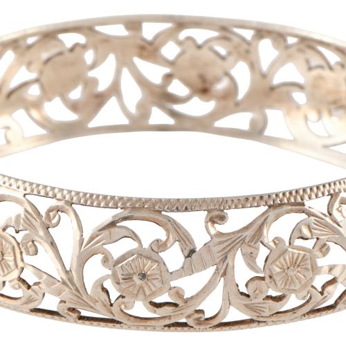 Pulsera ancha rígida calada con motivos florales.